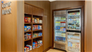 Corner market in the hotel that has various shelves with differnt snacks and two fridges of drinks a