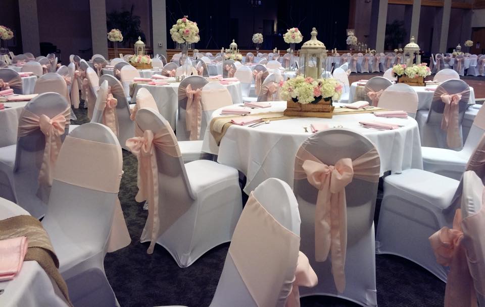 Pastel wedding reception of white and peach table settings and chairs