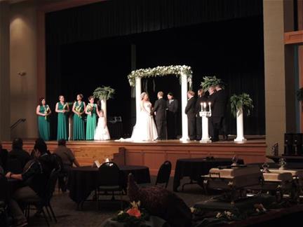 Wedding ceremony with couple and wedding party on a stage in the Great Hall